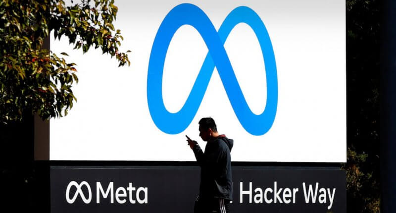 Homem passando em frente a letreiro com o logo da Meta, nova marca da empresa do Facebook