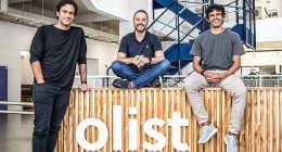 Líderes da Olist em frente ao logo da empresa, que anunciou a compra da Tiny ERP e Vnda Ecommerce