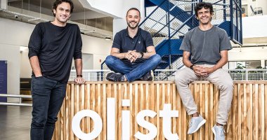 Líderes da Olist em frente ao logo da empresa, que anunciou a compra da Tiny ERP e Vnda Ecommerce