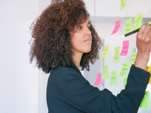 Mulher fazendo brainstorm para o planejamento de marketing de conteúdo com post its colados na parede