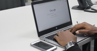 Homem fazendo busca no Google em um laptop