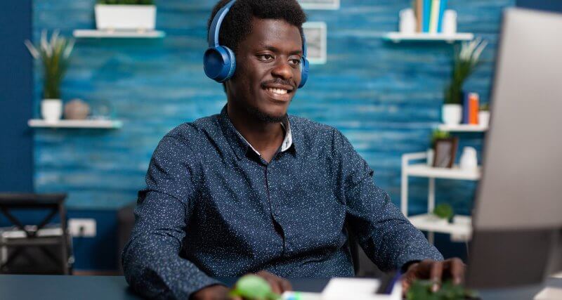 Homem usando fones de ouvido em frente ao computador para participar de um evento em áudio do LinkedIn