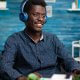 Homem usando fones de ouvido em frente ao computador para participar de um evento em áudio do LinkedIn